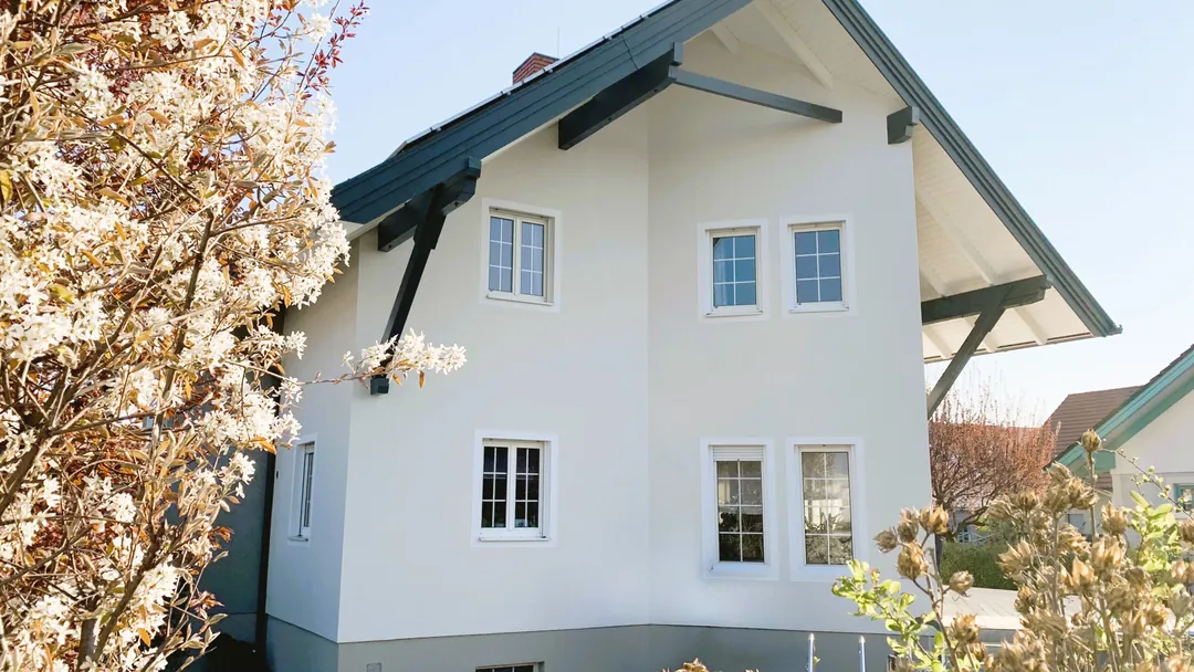 Saniertes Wohnhaus mit weißer Fassade und neuen Fenstern
